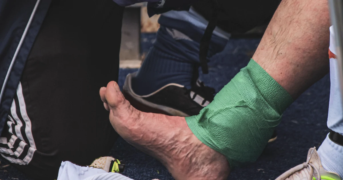 A soccer player’s injured ankle is wrapped on the sideline during a match.
