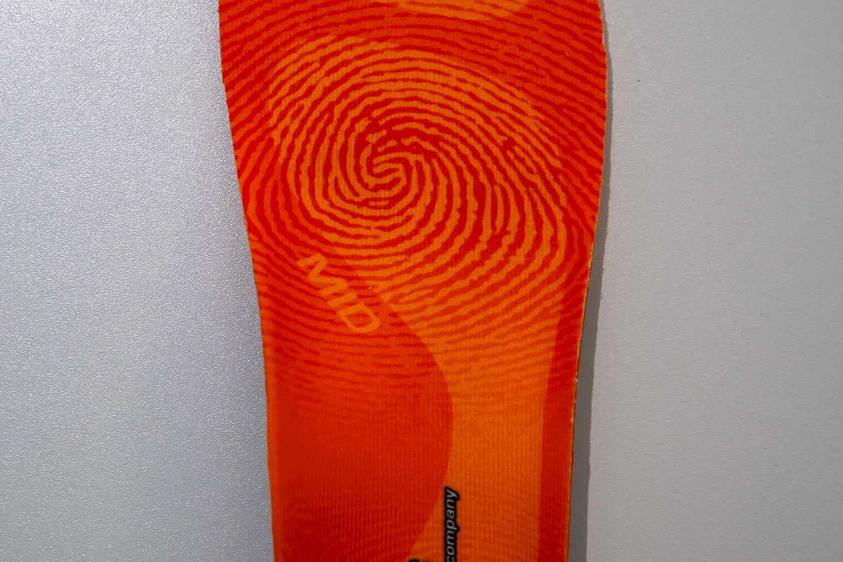 A supportive orange shoe insole photographed against a neutral background.